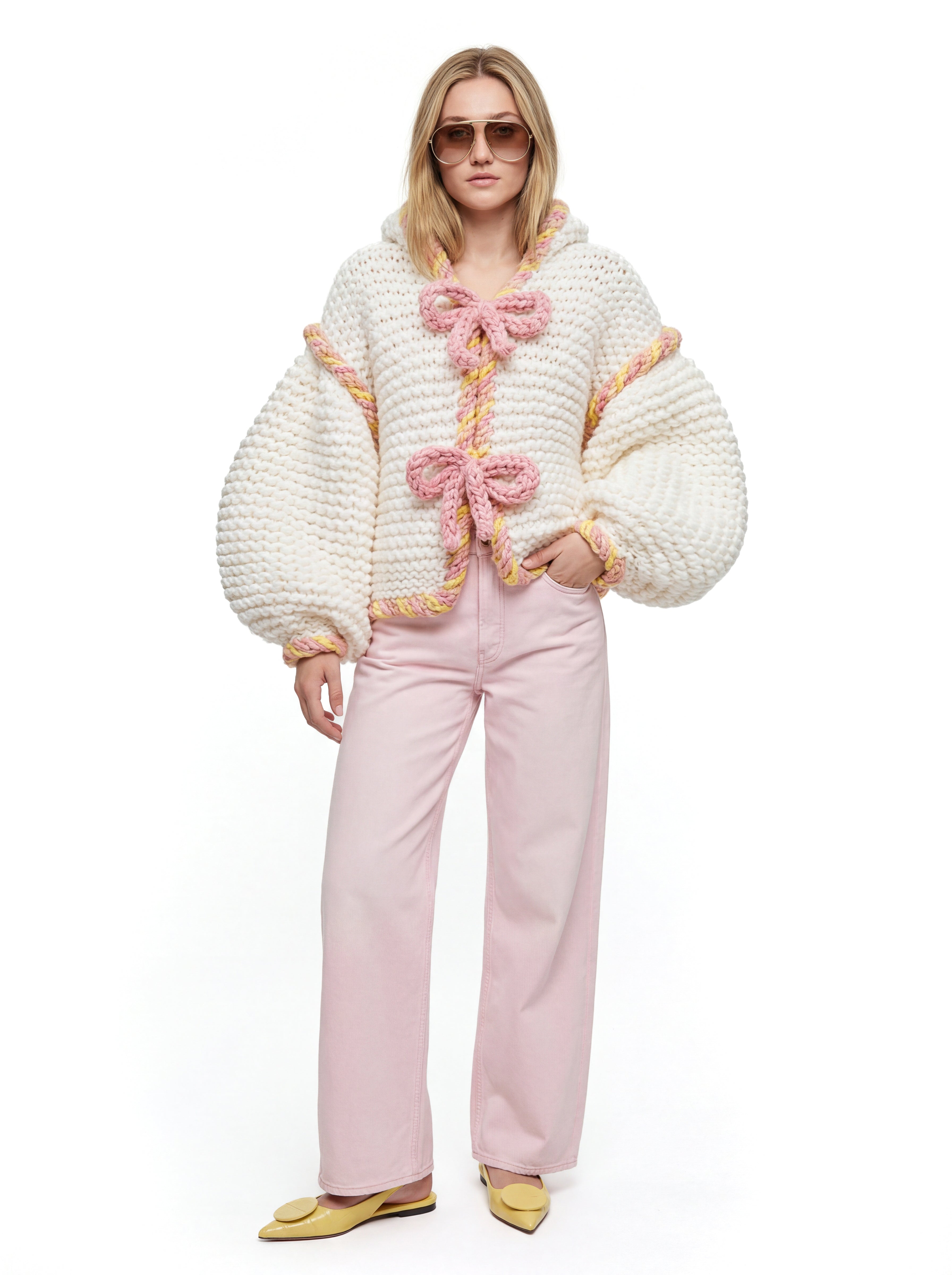 Woman wearing a textured white jacket with pink accents and pink pants on a white background