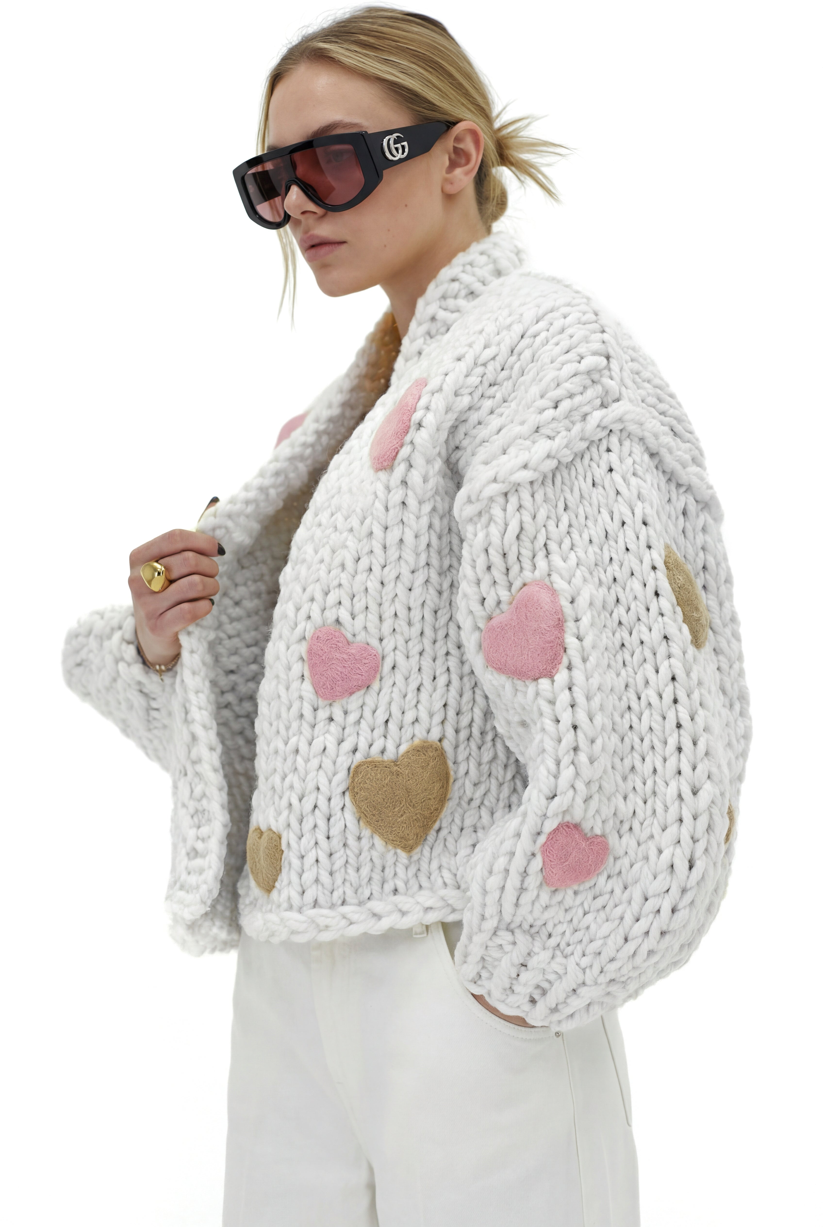 Person wearing a white knitted cardigan with heart patterns on a white background