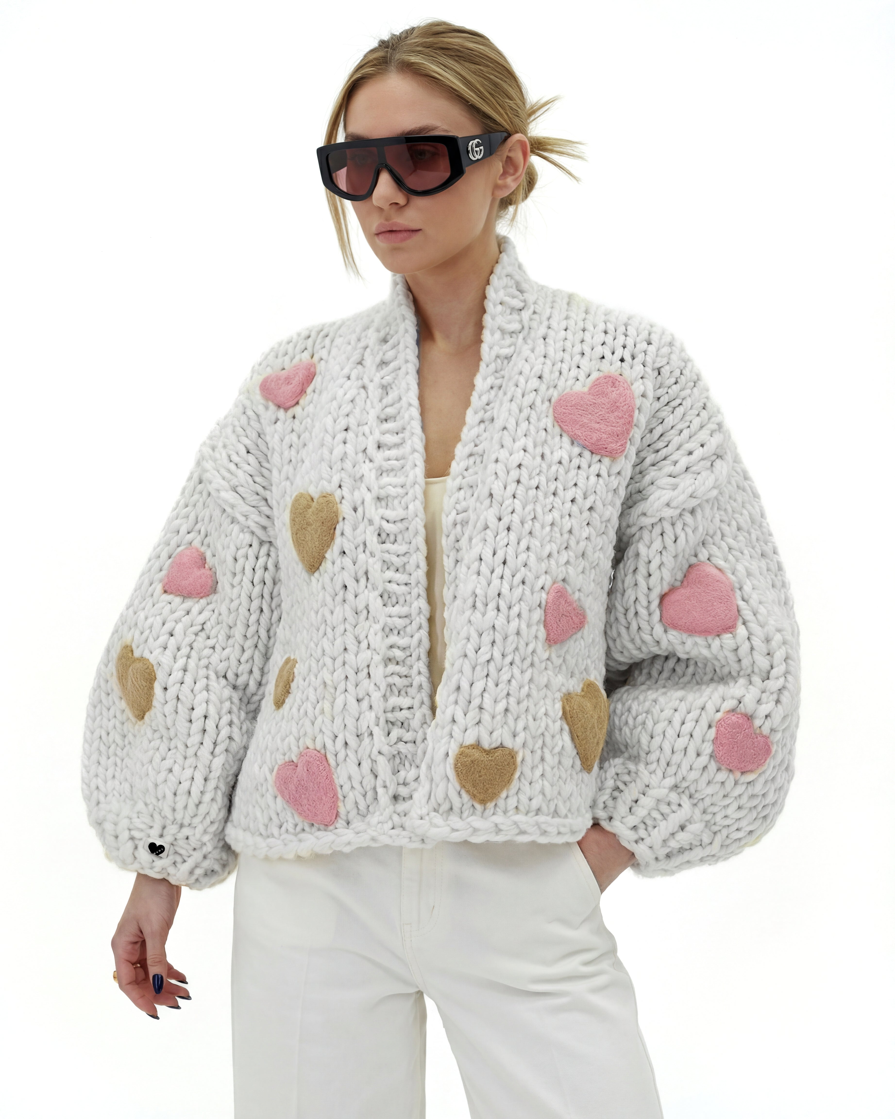 Woman wearing a luxury chunky knit cardigan with hearts one it  